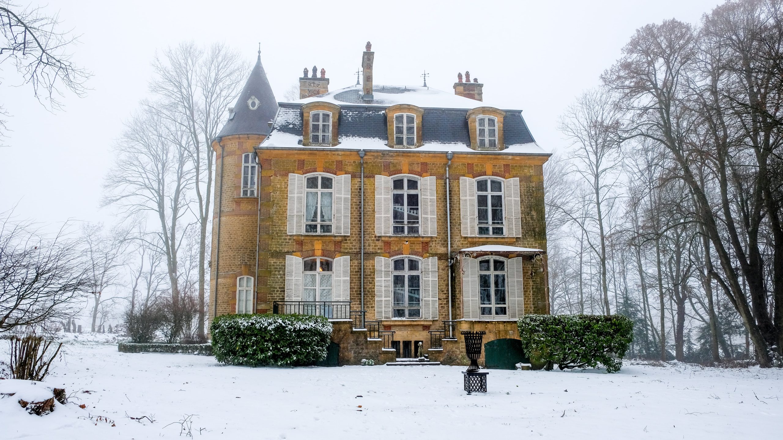 Château Guillermo in de Ardennen, omringd door besneeuwde bomen en een rustige wintertuin, gezien vanop de voorzijde.