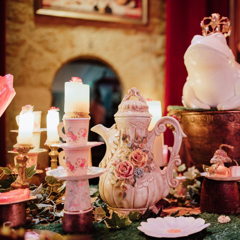Elegant spring decoration at Château Fort de Sedan featuring vintage floral teapot, pastel candles, and whimsical frog figurine during The Castle of Wonders event.